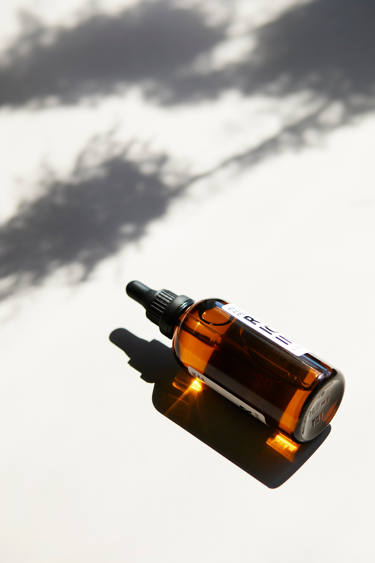 Butelka oleju Biorganique France leżące w słońcu na jasnym tle