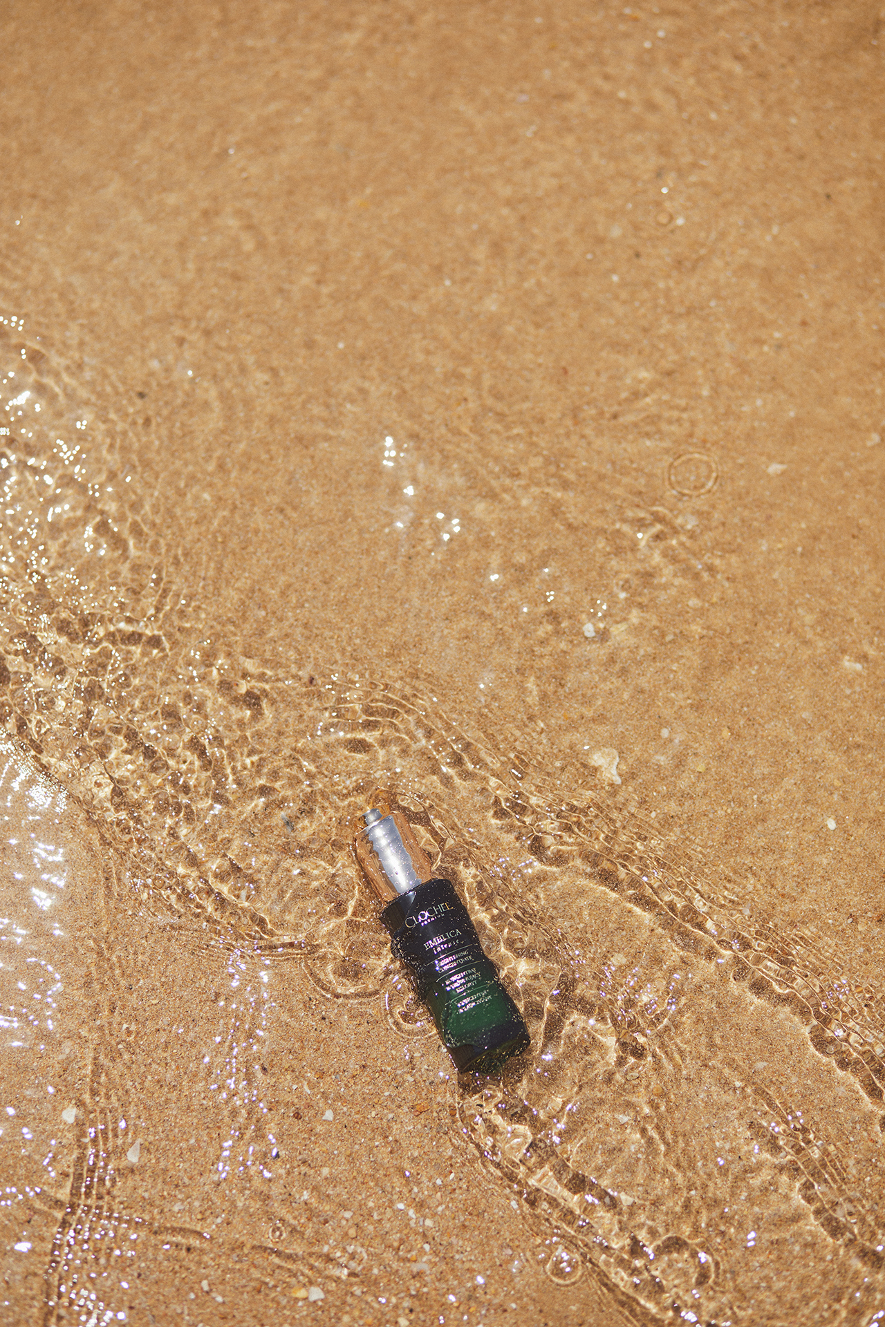 Produkt Clochcee Cosmetics na plaży zaniżony w wodzie