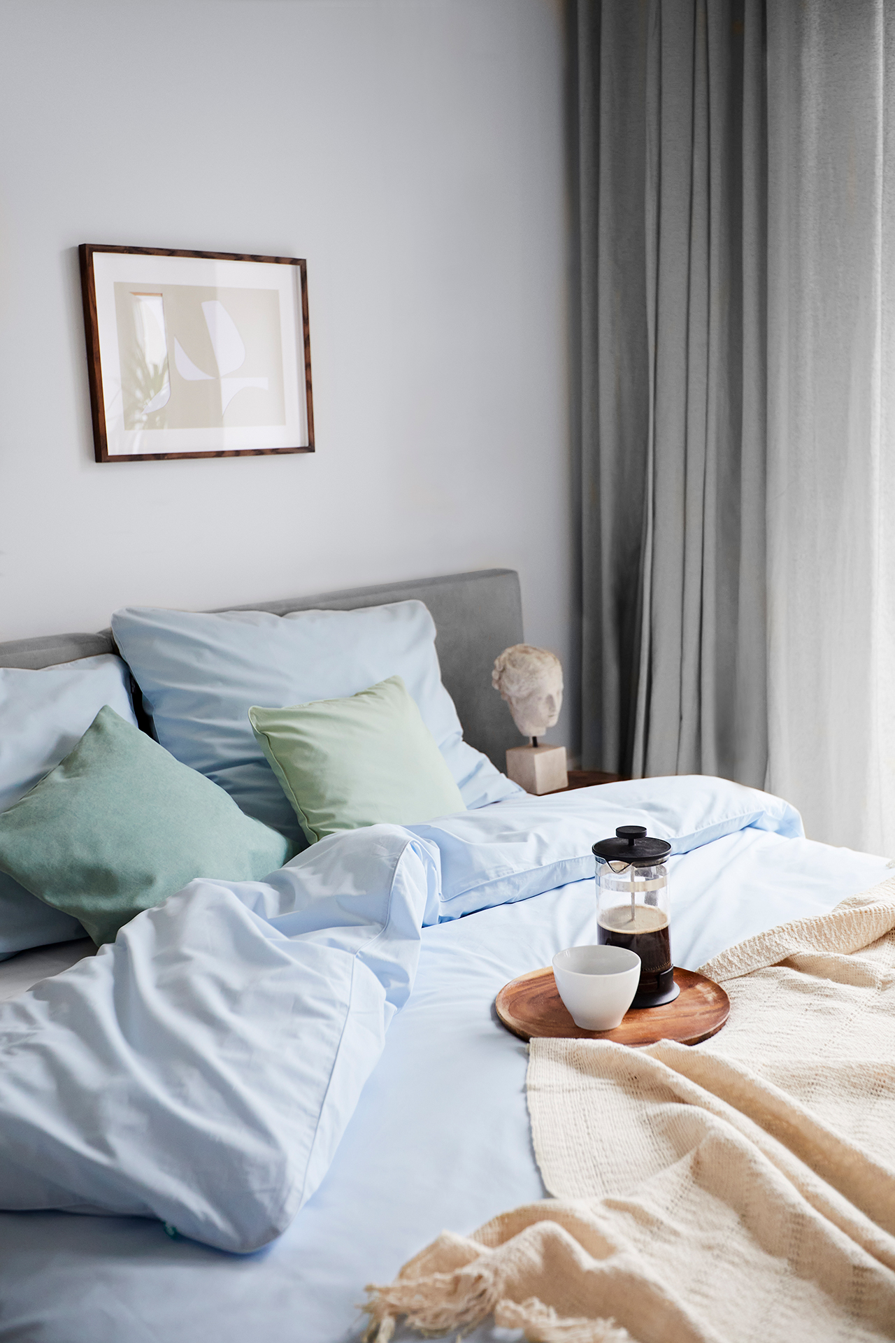 Kawa na podstawce, na łóżku z niebieską pościelą