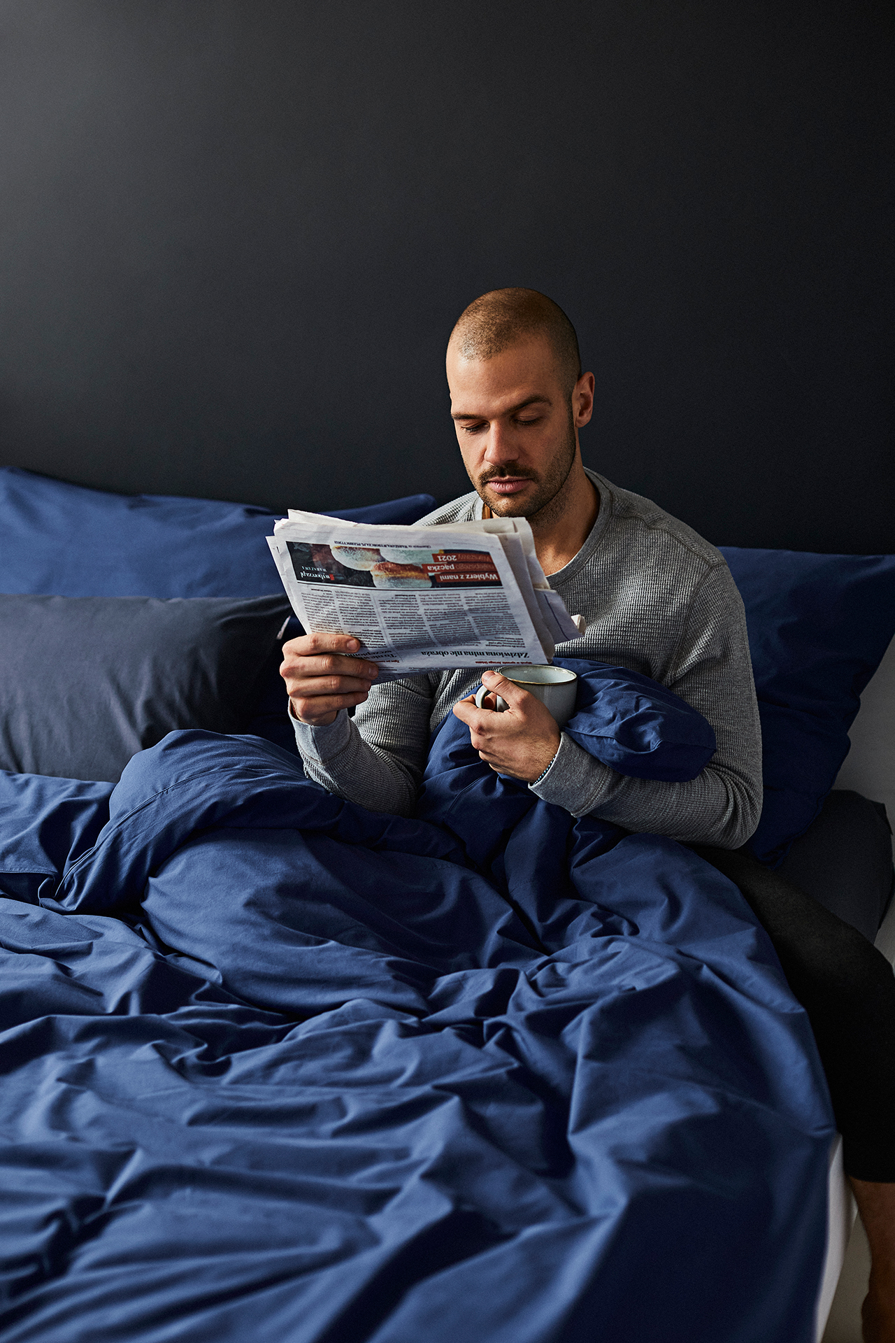 Chłopak na łóżku z gazetą